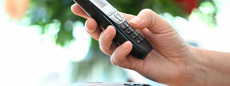 ILLUSTRATION - Eine Frau hölt ein Festnetz-Telefon in ihrer Hand.  - Foto: Bernd Weissbrod/dpa