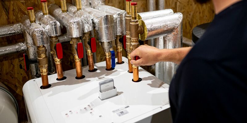 Ein Handwerker arbeitet an einer Wärmepumpe. Bei den Geräten ist die Nachfrage eingebrochen. - Foto: Fabian Sommer/dpa