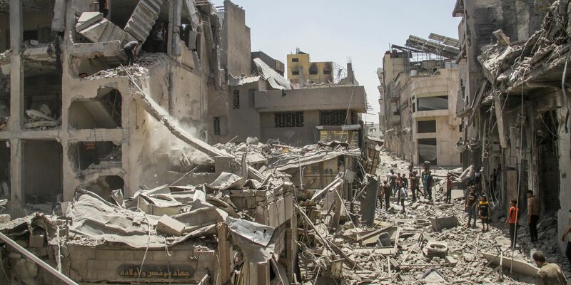 In der Stadt Gaza stehen Palästinenser inmitten zerstörter Gebäude - Foto: Mahmoud Zaki/XinHua/dpa