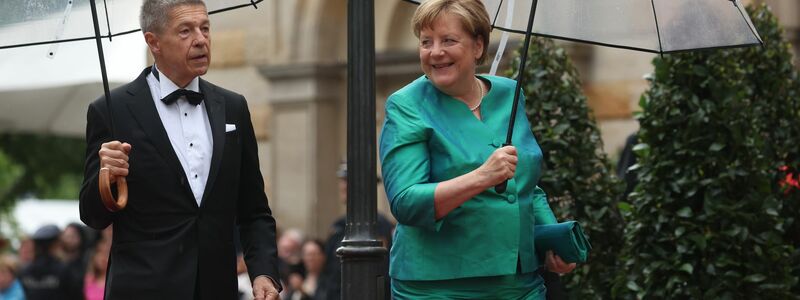 Im letzten Jahr mussten sich Angela Merkel und Ehemann Joachim Sauer auf den Weg ins Bayreuther Festspielhaus mit Regenschirmen schützen. (Archivfoto)  - Foto: Karl-Josef Hildenbrand/dpa