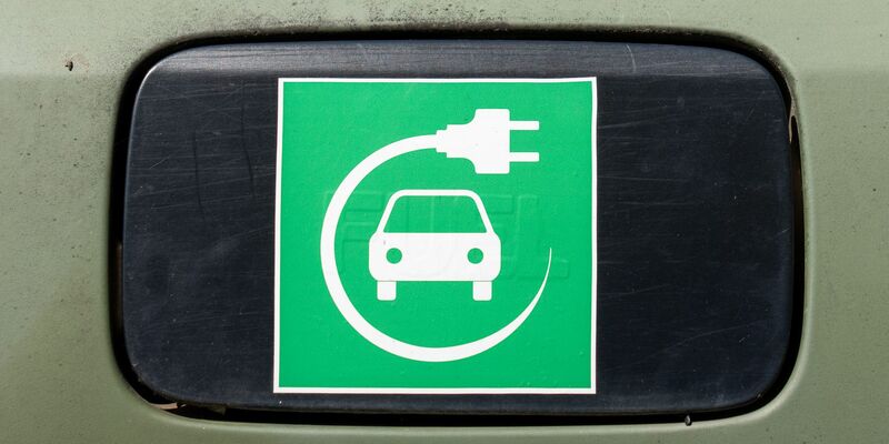 Ein Elektroauto-Symbol auf einem Auto.  - Foto: Soeren Stache/dpa