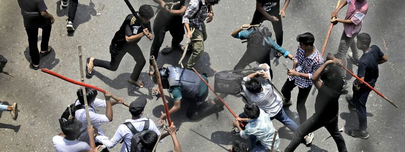 Studenten schlagen einen Polizisten mit Stöcken - Foto: Anik Rahman/AP/dpa