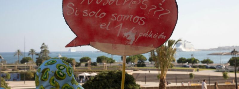 Einheimische auf Mallorca halten ein Schild, auf dem steht: «Verschmutzen? Wir??? Wo wir nur 1,2 (Millionen) Einwohner sind.» - Foto: Clara Margais/dpa