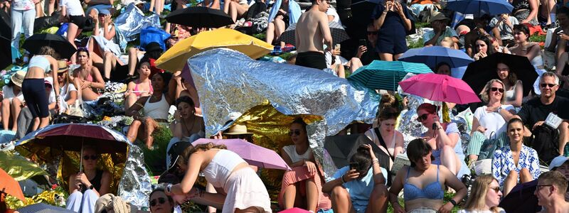 Mit Schirmen versuchten viele Fans, sich vor der Sonne zu schützen. - Foto: Felix Hörhager/dpa