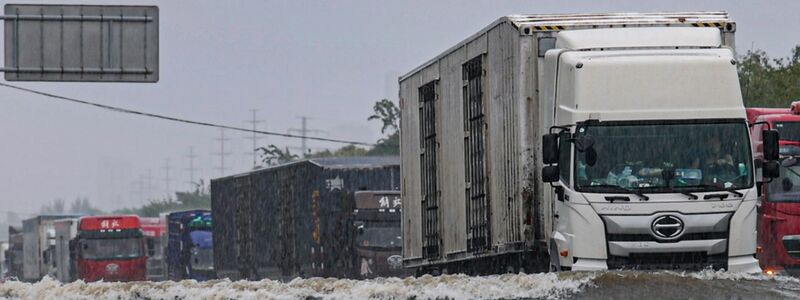 Große Lastwagen fahren durch ein Hochwasser in Shenyang in der nordostchinesischen Provinz Liaoning. - Foto: Wang Hongtao/Xinhua/AP