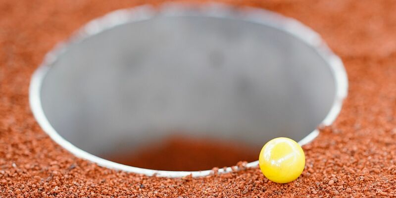 Die Murmeln müssen in das Loch (eine Kuhle) auf dem drei Mal sechs Meter großen Feld befördert werden. - Foto: Uwe Anspach/dpa