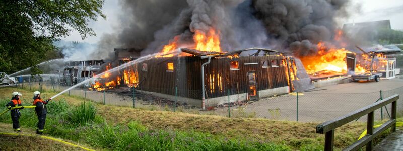 Einsatzkräfte löschen eine brennende Lagerhalle mit Fahrzeugen in Untermerzbach - Foto: Pia Bayer/dpa