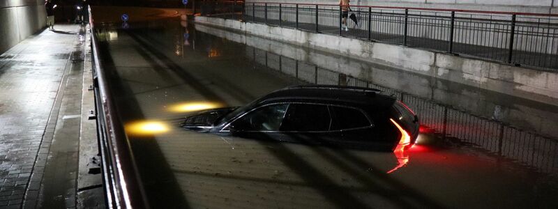 Nach einem schweren Gewitter steht ein Auto in Bruchsal bis zur Motorhaube im Wasser. - Foto: René Priebe/dpa