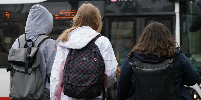 Zwei Schülerinnen und ein Schüler warten in Hamburg auf einen Bus. (Symbolbild) - Foto: Marcus Brandt/dpa