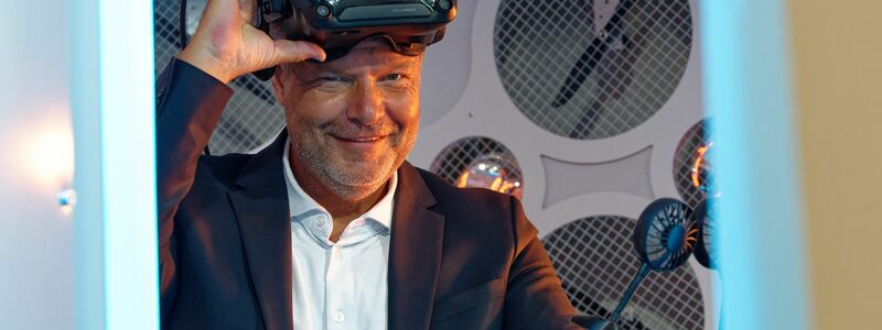 Wirtschaftsminister Robert Habeck (Grüne) steht bei einem Messerundgang bei der Computerspiele-Messe Gamescom 2022 in einem Simulator und trägt dabei eine Virtual-Reality-Brille. - Foto: Henning Kaiser/dpa