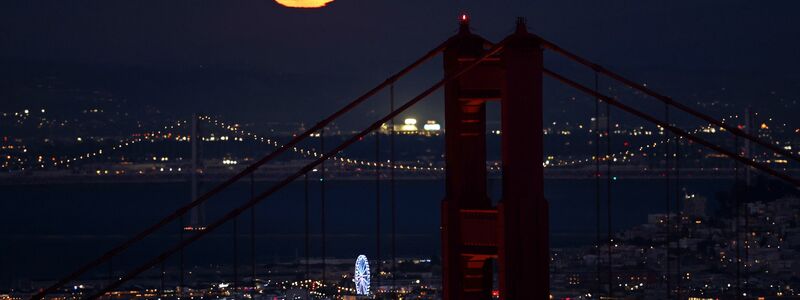 Hinter der Golden Gate Bridge ist am Himmel ein goldfarbener Vollmond zu sehen - Foto: Scott Strazzante/San Francisco Chronicle/AP/dpa