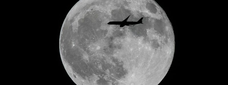 Ein Flugzeug fliegt an einem großen Vollmond vorbei. - Foto: Ringo Chiu/SOPA Images/ZUMA Press Wire/dpa