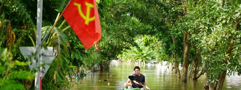 Ein Mann paddelt in der Nähe von Hanoi durch das Hochwasser. - Foto: Hau Dinh/AP/dpa