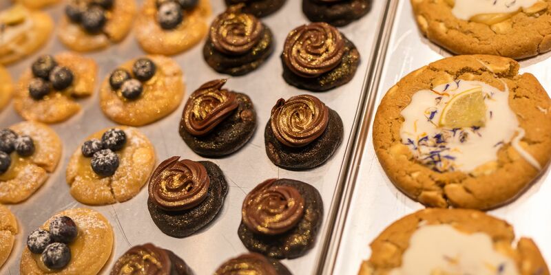 Eine Box mit frisch gebackenen und belegten Cookies präsentiert Mitgründerin Julia Boes. - Foto: Christoph Schmidt/dpa