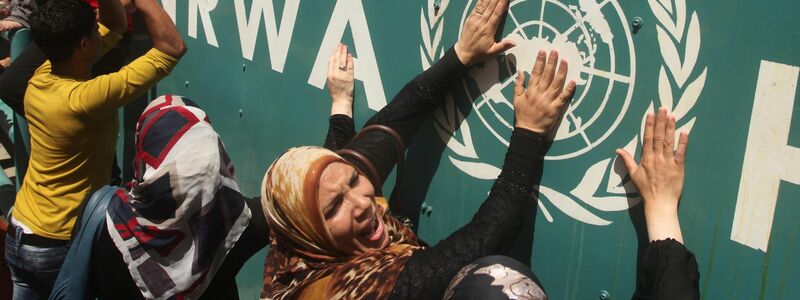 Palästinenserinnen vor UNRWA-Schild (Archivbild) - Foto: Ashraf Amra/APA Images via ZUMA Wire/dpa