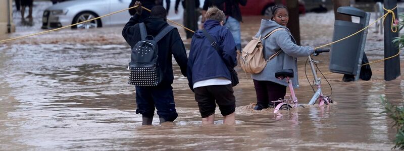 Menschen gehen durch überflutete Straßen. - Foto: ALberto Saiz/AP