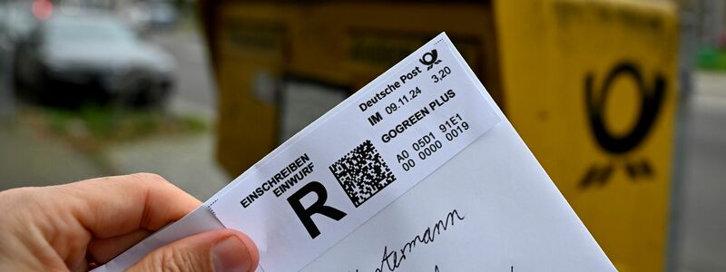 Ein Mann hält ein sogenanntes Einwurf-Einschreiben vor einen Briefkasten (gestellte Szene). - Foto: Wolf von Dewitz/dpa