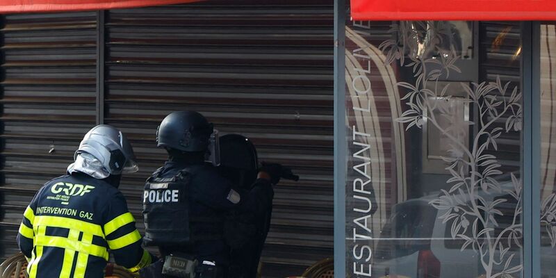 Polizisten stehen vor dem Restaurant in Issy-les-Moulineaux. - Foto: Ian Langsdon/AFP/dpa