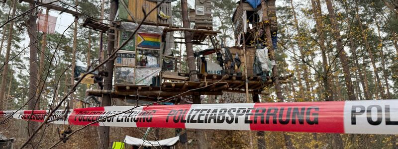 Polizeikräfte sichern das Waldgebiet hinter einer Absperrung. Umweltaktivisten, die gegen Tesla protestieren, müssen ihr Camp räumen.  - Foto: Lutz Deckwerth/dpa