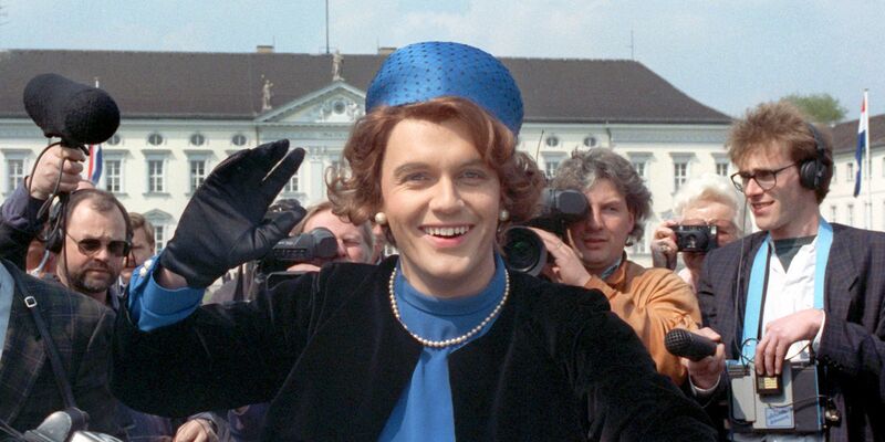 Verkleidet als Königin Beatrix winkt der deutsche Komiker und Showmaster Hape Kerkeling vor Schloss Bellevue für die Presse. (Archivfoto von 1991) - Foto: picture alliance / dpa