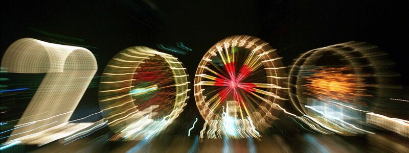 25 Jahre alt ist dieses «2000»-Foto: Ein Zoom-Effekt verfremdet eine große «2» und drei Riesenräder am Mainufer in Frankfurt in der Silvesternacht 1999/2000.  - Foto: Arne Dedert/dpa