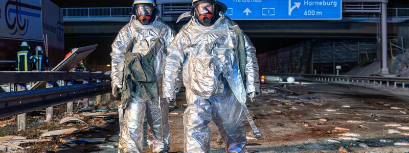 Überall Fische auf der Fahrbahn: Bei dem Unfall auf der A1 mussten Feuerwehrleute die Unfallstelle zunächst in speziellen Schutzanzügen sichern.  - Foto: JOTO/dpa