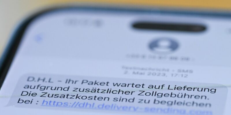 Auf einem Smartphone ist eine Betrugs-SMS zu lesen, in der Kriminelle ein Paket ankündigen und dafür Zollgebühren einfordern.  - Foto: Wolf von Dewitz/dpa