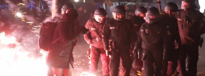 Polizei zwischen brennendem Feuerwerk auf der Straße in Berlin in der Silvesternacht.  - Foto: Julius Schreiner/dpa