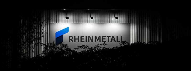 Das beleuchtete Logo und der Schriftzug der Rüstungsfirma Rheinmetall hängt an einer Produktionshalle. - Foto: Lars Penning/dpa