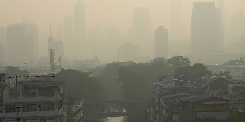 Pendler tragen Gesichtsmasken, um sich vor der Luftverschmutzung zu schützen. - Foto: Sakchai Lalit/AP/dpa
