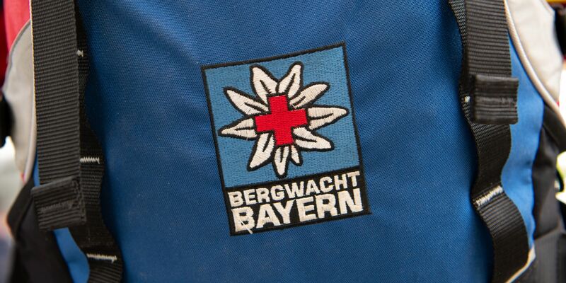 Das Logo der Bergwacht ist an einem Rucksack zu sehen. Bei Oberstdorf musste die Bergwacht nun einen Mann retten, der ohne richtige Ausrüstung und Erfahrung zwei Nächte in den Bergen verbrachte. (Archivfoto-Illustration) - Foto: Sven Hoppe/dpa