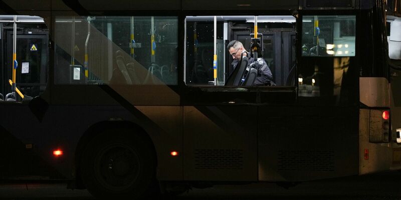 Ein Polizeibeamter inspiziert einen Bus.  - Foto: Ohad Zwigenberg/AP/dpa