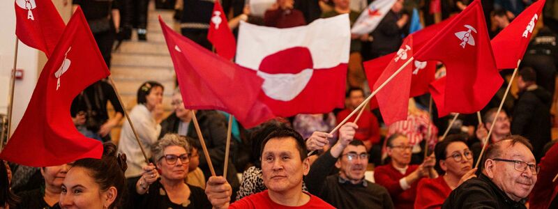 Grönländer schwenken während einer TV-Debatte diverse Flaggen. - Foto: Evgeniy Maloletka/AP/dpa