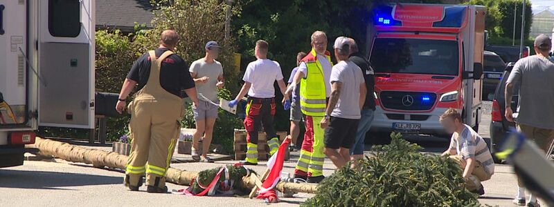 Der umgestürzte Maibaum liegt auf der Straße vor einem Einsatzwagen der Feuerwehr.  - Foto: Guido Schulmann/TV-Niederrhein/dpa