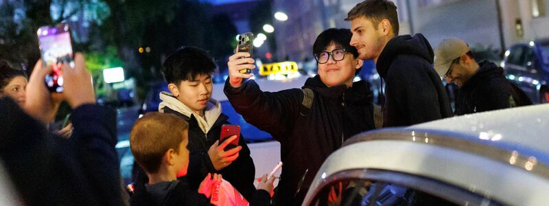 Torhüter Jonas Urbig schreibt Autogramme, bevor er mit seinen Teamkollegen feiert.  - Foto: Matthias Balk/dpa