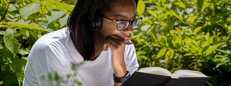 Junge Frau sitzt im Grünen und liest ein Buch.  - Foto: Pixabay@terski