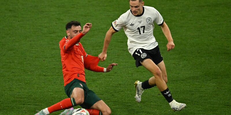 Nick Woltemade (l) hatte bei seinem Länderspiel-Debüt gegen Portugals Abwehrrecken einen schweren Stand. - Foto: Peter Kneffel/dpa