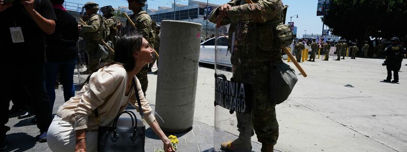 Eine Frau legt Blumen vor der Nationalgarde nieder.  - Foto: Damian Dovarganes/AP/dpa