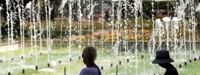 Zwei Frauen sitzen an einem Springbrunnen im egapark in Erfurt in Thüringen. - Foto: Michael Reichel/dpa