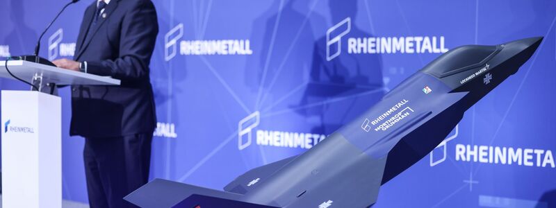 Ein Modell des F-35 auf der Bühne, auf der Konzernchef Papperger zu Mitarbeitern spricht. - Foto: Oliver Berg/dpa