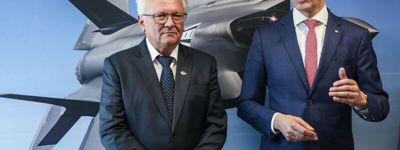 Papperger und Wüst vor einem Bild des F-35-Flugzeugs. Ende nächsten Jahres soll das erste Rumpfmittelteil dieses Tarnkappenbombers in Weeze fertig sein. - Foto: Oliver Berg/dpa