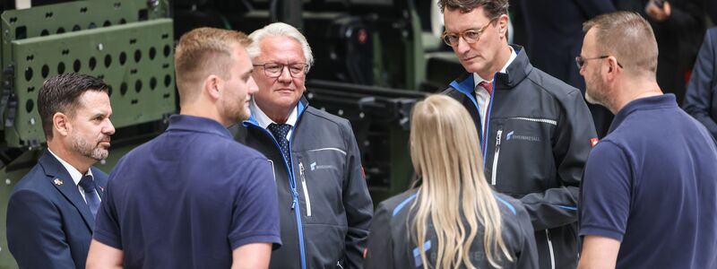 Rheinmetall-Chef Armin Papperger (Dritter von links) und NRW-Ministerpräsident Hendrik Wüst (zweiter von rechts) bei einem Rundgang durch die F-35-Produktionsanlage. - Foto: Oliver Berg/dpa