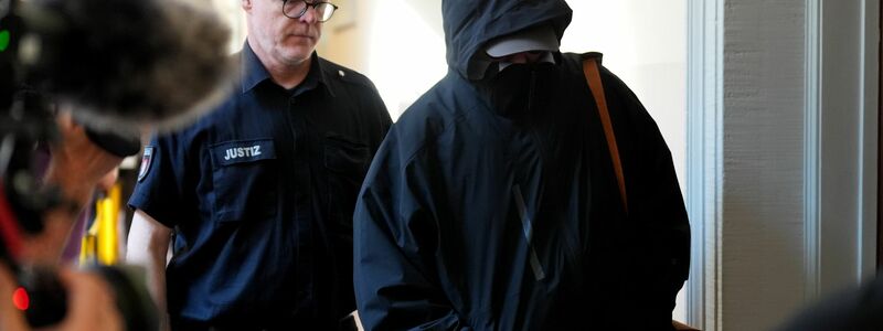 Ein Angeklagter wird von einem Polizisten zum Gerichtssaal begleitet.  - Foto: Marcus Brandt/dpa