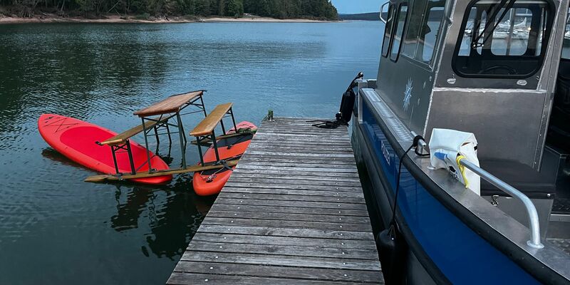 Das Trio war auf einer Konstruktion aus Surfbrettern und einer Bierbank auf dem Brombachsee unterwegs. Bild: Polizei Mittelfranken - Foto: -/Polizei Mittelfranken/dpa