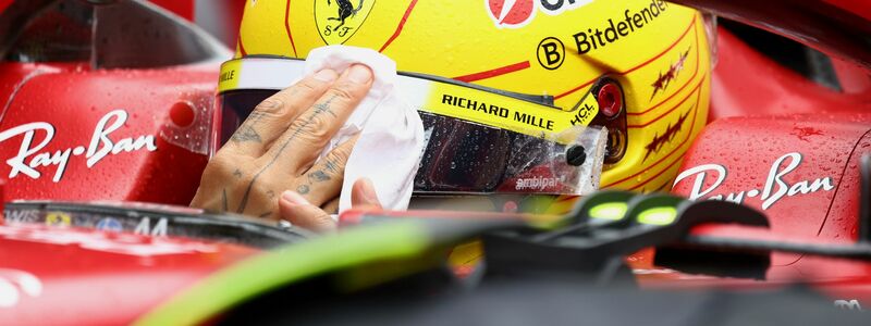 Lewis Hamilton wischt sich den Regen vom Visier. - Foto: Yves Herman/Pool Reuters/AP/dpa