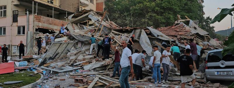 Menschen beseitigen in Sindirgi die Trümmer eines eingestürzten Gebäudes. - Foto: Bahadir Demirceviren/IHA/AP/dpa
