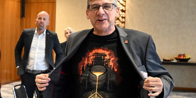 Zum Beginn der Tarifverhandlungen in der Stahlindustrie überreicht der Verhandlungsführer der IG Metall, Knut Giesler, zwei T-Shirts an den Verhandlungsführer der Arbeitgeber, Reiner Blaschek (2.v.l), sowie den Geschäftsführer des Arbeitgeberverbandes Stahl, Gerhard Erdmann (l). - Foto: Federico Gambarini/dpa