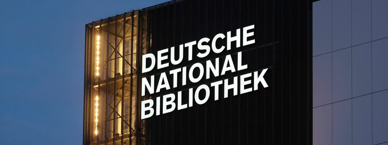 Der Schriftzug Deutsche Nationalbibliothek (DNB) leuchtet an einem 55 Meter hohen Gebäude der früheren Deutschen Bücherei. (Archivbild) - Foto: Sebastian Willnow/dpa
