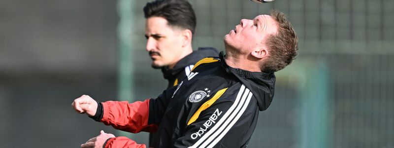 Mit Teamarzt Hahne (2.v.l.) betritt Schlotterbeck (l.) den Trainingsplatz. - Foto: David Inderlied/dpa