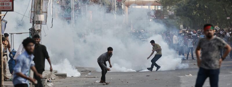 Demonstranten werfen Steine und rufen Parolen während einer Auseinandersetzung mit der Polizei in Bangladesch. - Foto: Rajib Dhar/AP/dpa